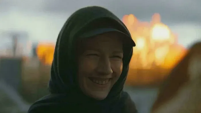 Mysterious hooded figure stands before glowing fire in Project Hail Mary.