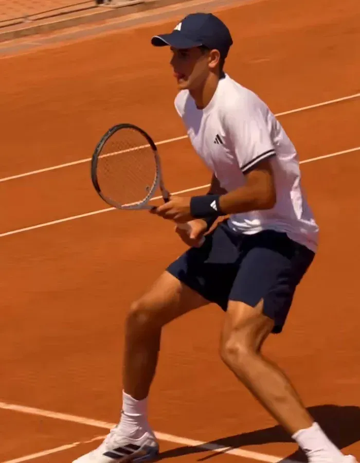 Young tennis player preparing return shot on clay court