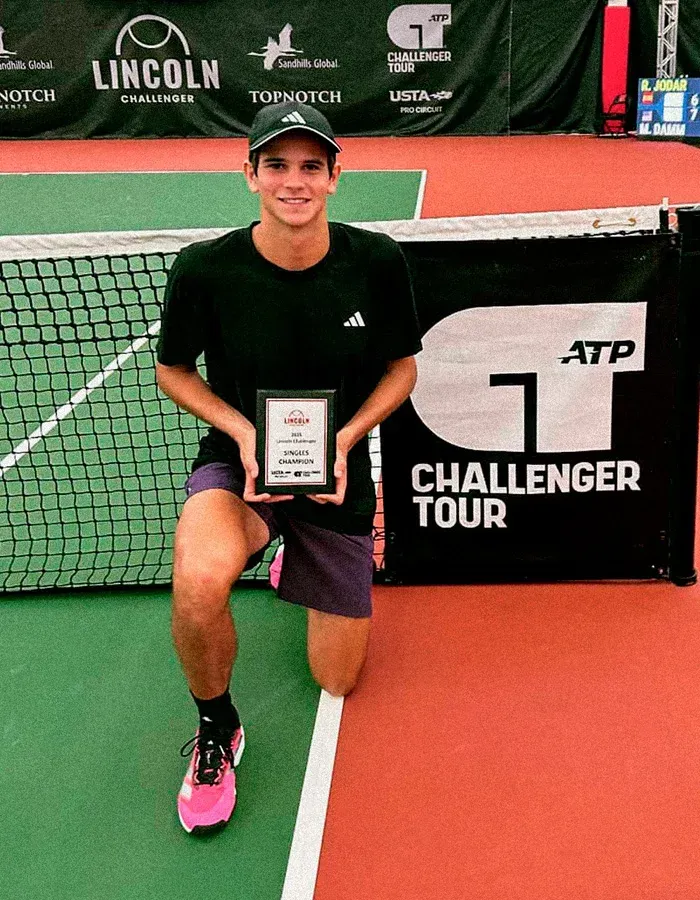 Young champion posing with ATP Challenger tournament trophy after victory