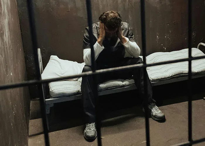 Man in prison cell reflecting on consequences