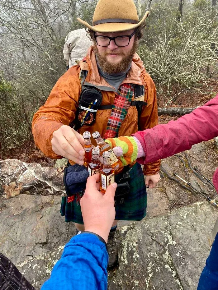 Hikers toasting with miniature liquor bottles in the outdoors