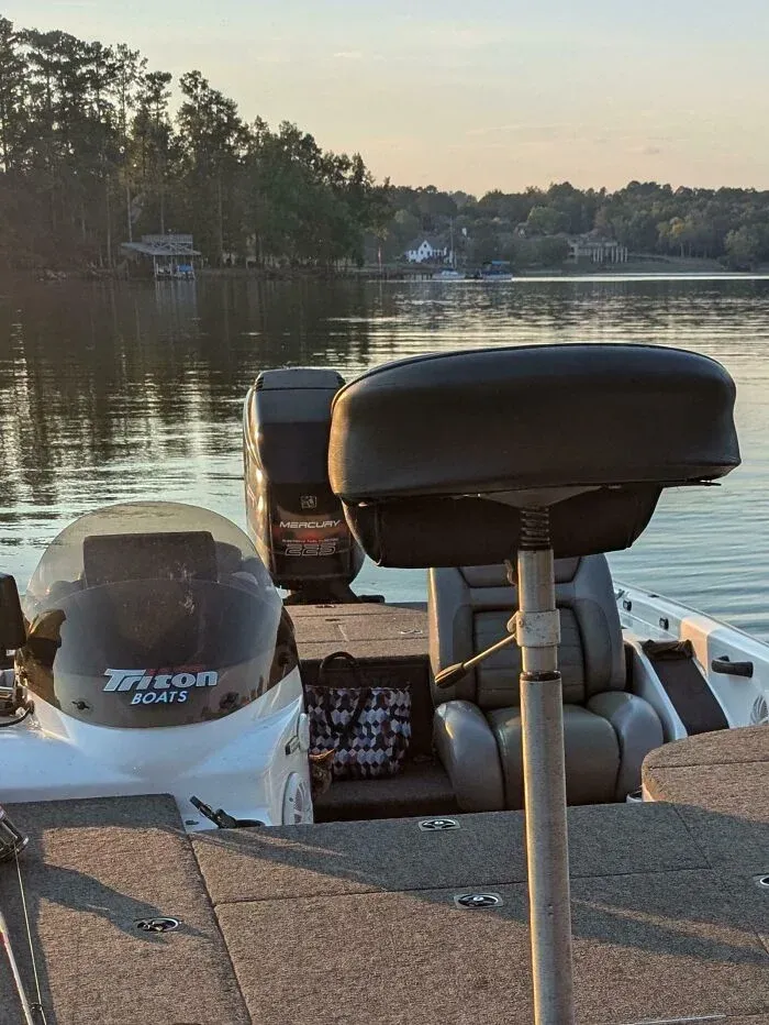 Fishing boat on calm lake water near tree-lined shore at sunset